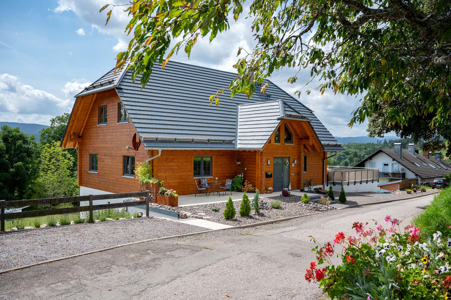 Traditionelles Holzhaus von Fullwood im Stil eines Schwarzwaldhofs mit weit heruntergezogenem Satteldach, dunkler Holzfassade und natürlicher Umgebung